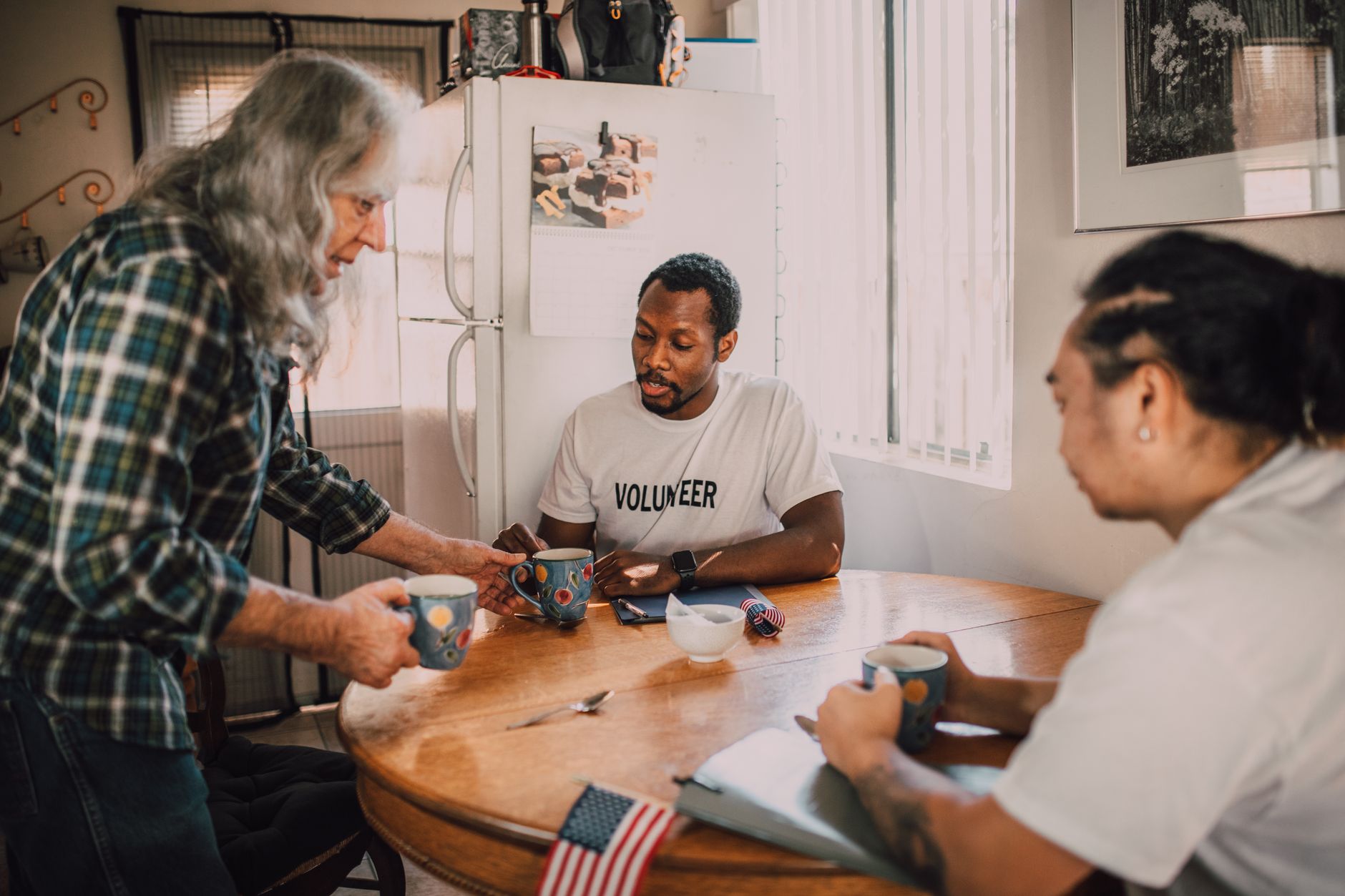 Three volunteers talking over coffee in a bright room